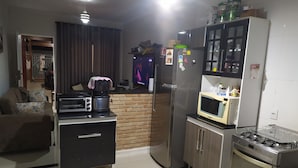Eine kleine Küche mit Kühlschrank, Mikrowelle, Herd und Kaffeemaschine.