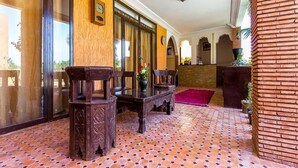 En entréhall med ett klinkergolv, trämöbler och en tegelvägg.