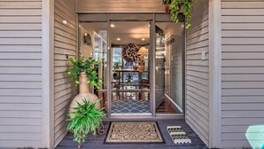 A modern house entrance with a glass door, potted plants, a decorative clock, and a rug. - Hot Tub, Game Room & Sauna: Ruidoso Hideaway! (Ruidoso)