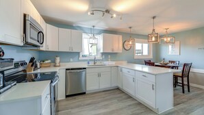 A modern kitchen with white cabinetry, stainless steel appliances, and pendant lighting. - Walkable & Renovated! Salter Path Retreat w/ Deck (Atlantic Beach)