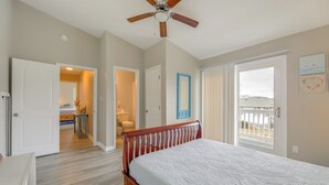 A bedroom with a wooden bed, a ceiling fan, and a view of the outside. - Walkable & Renovated! Salter Path Retreat w/ Deck (Atlantic Beach)