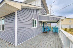 Ein zweistöckiges Haus mit überdachter Veranda und blauem Gartenmöbel.