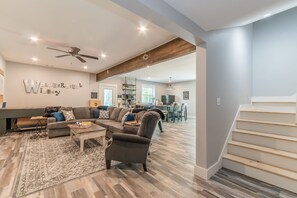 A spacious living room with a sofa, coffee table, and a rug. There is a staircase leading to another level.