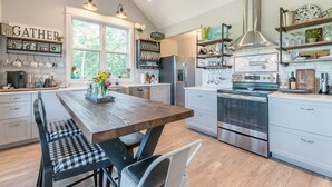 Una cocina moderna con una isla central, electrodomésticos de acero inoxidable y una variedad de utensilios de cocina exhibidos en estantes.