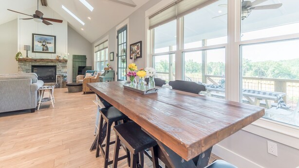 Una cocina espaciosa con una larga mesa de madera, ventanas amplias y una chimenea.