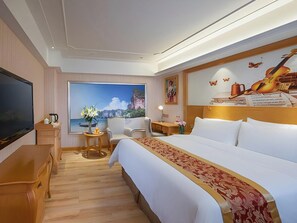 A hotel room with a large bed, a television, a desk, a chair, a small table with a vase of flowers, and a large window with a scenic view. - Venus International Hotel Shenzhen Gongming Square Metro Station Tianhong Branch (Shenzhen)