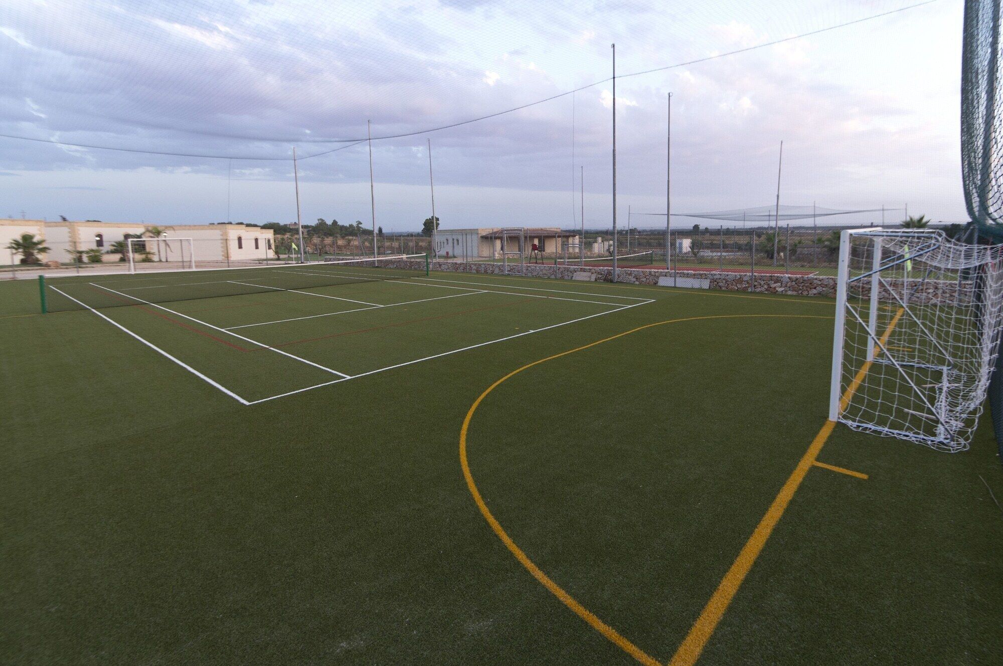 Un campo deportivo con postes de portería y una red, rodeado por una valla.