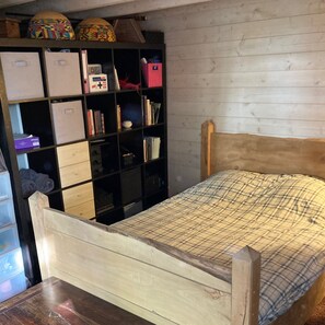 Ein Schlafzimmer mit einem hölzernen Bett, einer schwarzen Stauraum-Einheit mit verschiedenen Fächern und einer weißen Holzverkleidung.