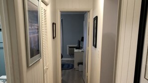En smal hall med trägolv, vita väggar och inramade tavlor på väggarna.