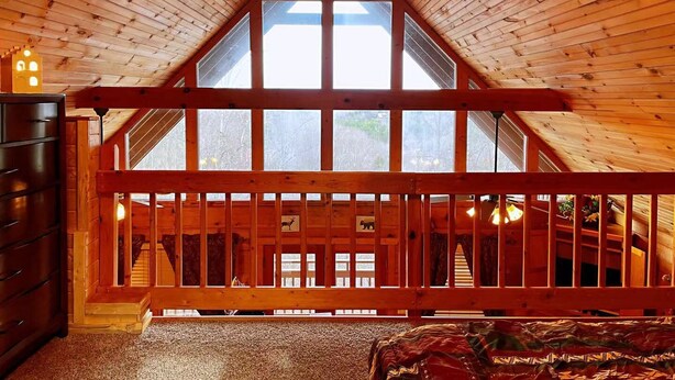 A wooden cabin with a sloped ceiling, a wooden staircase, and a large window. - Mountain Views ** Close2 Parkway/Gatlinburg/Dollywood ** | TreeHouse  (Sevierville)