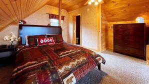 A cozy bedroom with a wooden ceiling, a bed with a patterned quilt, a dresser, and a ceiling fan. - Mountain Views ** Close2 Parkway/Gatlinburg/Dollywood ** | TreeHouse  (Sevierville)