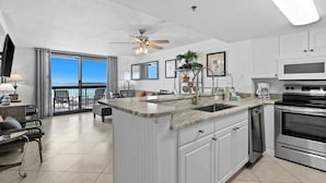 A modern kitchen with a large island, stainless steel appliances, and a view to the outside. - SunDestin 1BR Beach Retreat With Relaxing Gulf-Front Balcony - Unit 0306 (Destin)