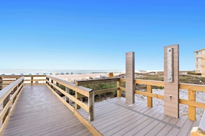 A wooden boardwalk leading to a beach with a clear sky.