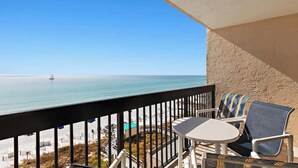 A balcony with a view of the sea, a table, and two chairs. - Beachfront 1BR Condo With Balcony, King Bed and Coastal Style (Destin)
