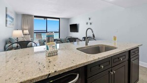 A modern kitchen with granite countertops, a stainless steel sink, and dark cabinetry.