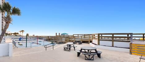 A rooftop pool area with picnic tables and a wooden deck.