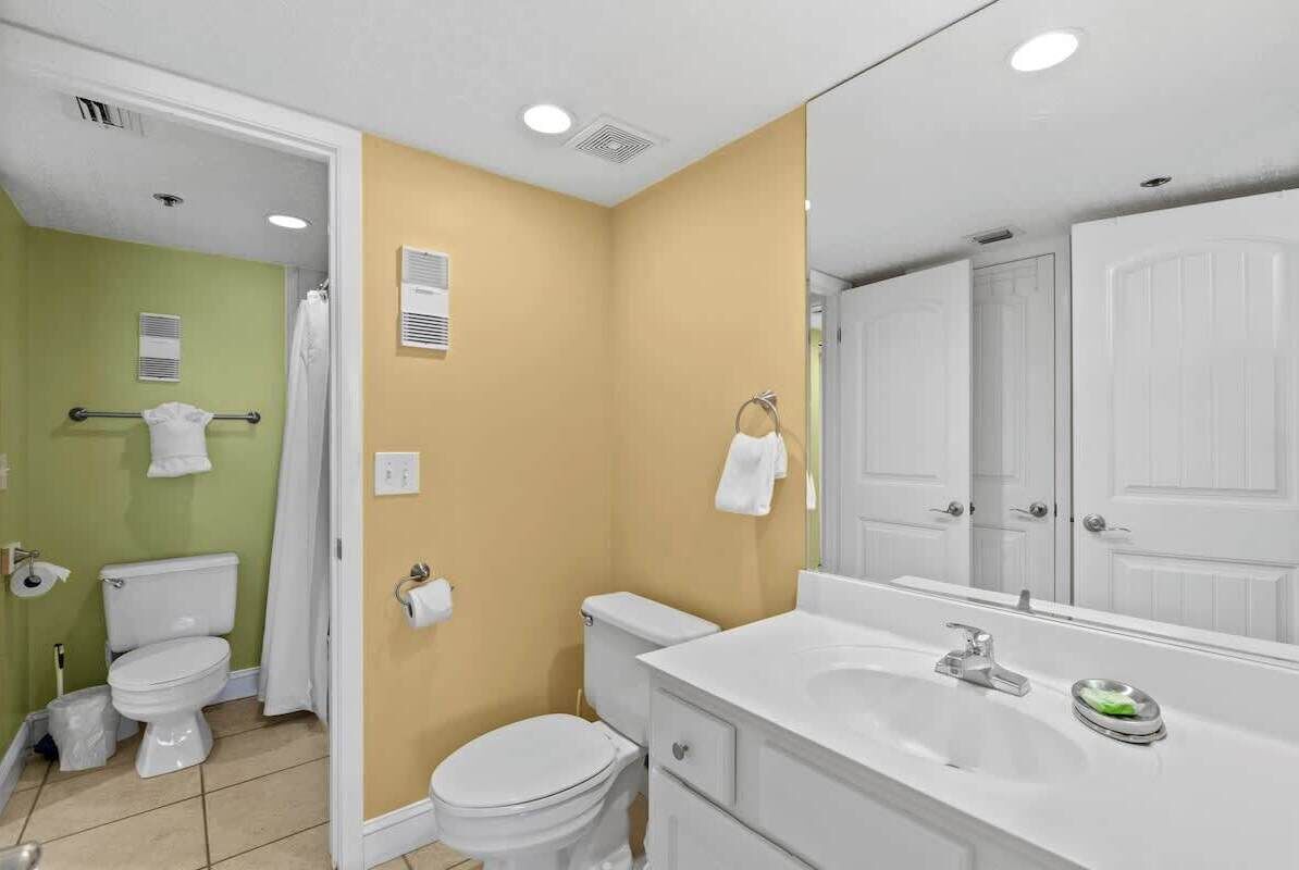 Une salle de bain avec deux toilettes, un lavabo et un miroir.