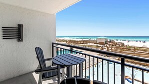 Un balcón con vista a la playa, una piscina y una silla.