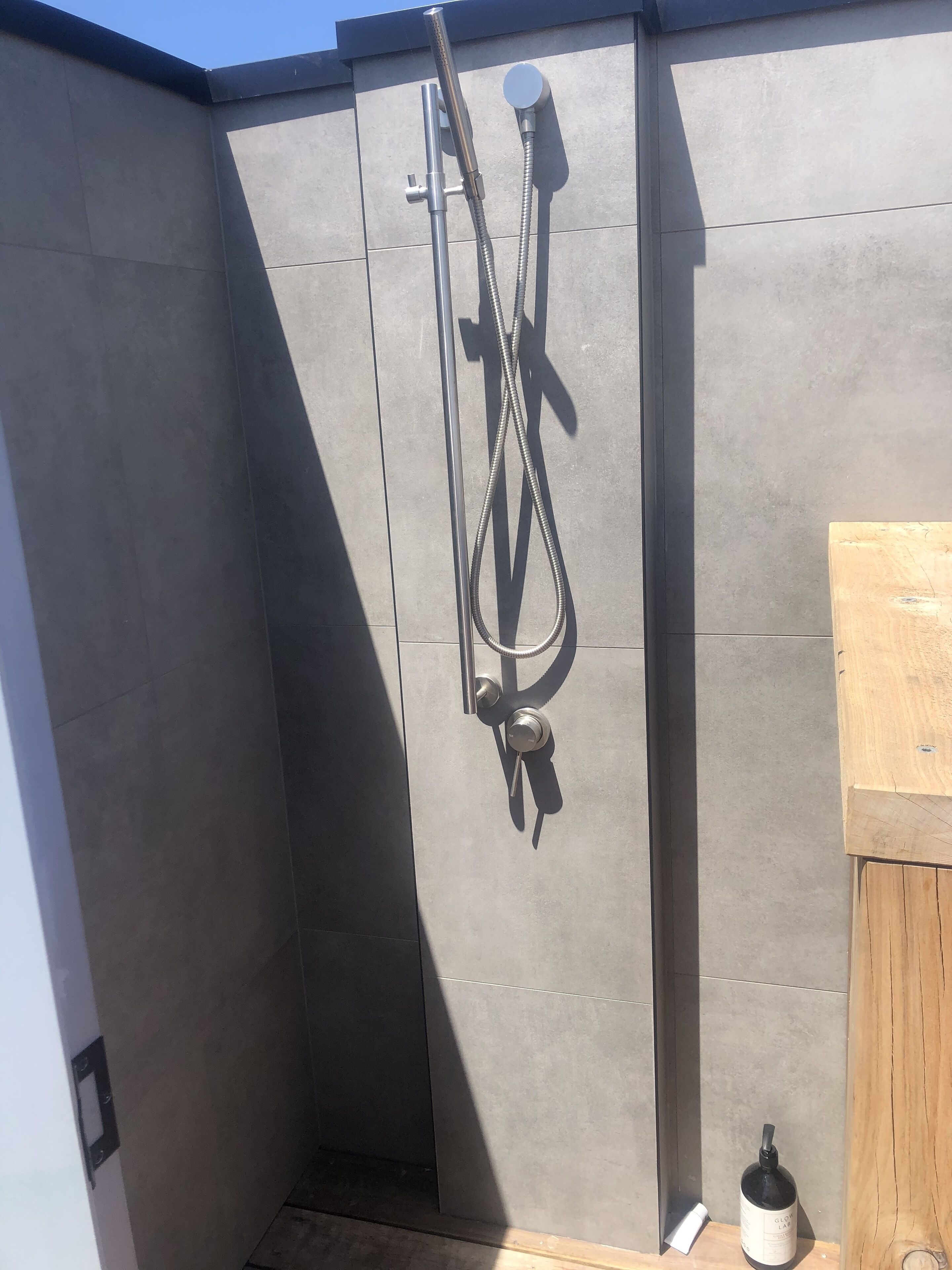 A shower area with a handheld showerhead and a wall-mounted faucet.