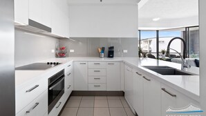 Een moderne keuken met witte kasten, een inbouwoven en een spoelbak.