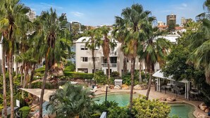 A resort with a swimming pool, palm trees, and modern buildings in the background. - Executive Three Bedroom Unit overlooking Resort Style Pool and Parking   (Kangaroo Point)