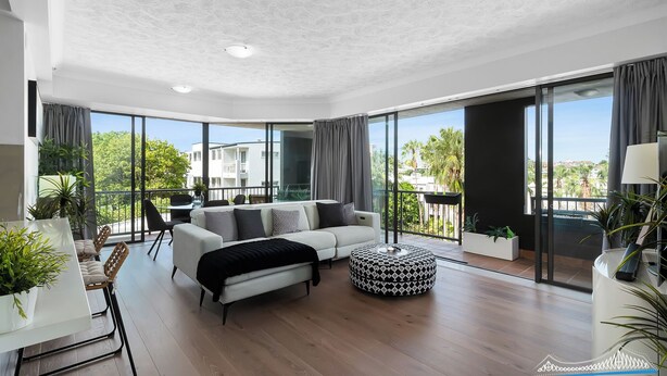 Een moderne woonkamer met een bank, een poef en een eethoek.