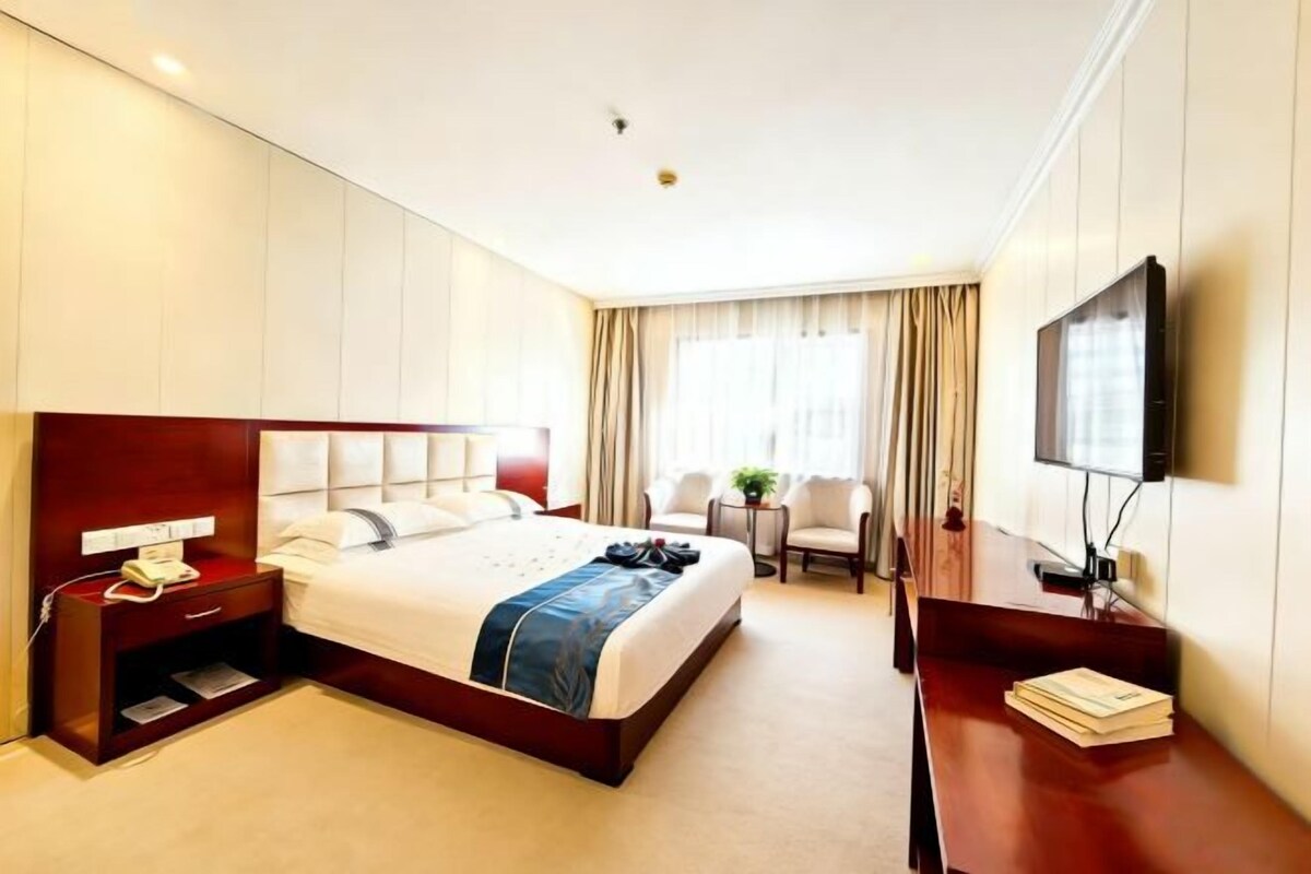 Une chambre d’hôtel équipée d’un lit, d’une table de chevet, d’une télévision, d’un bureau et de chaises.
