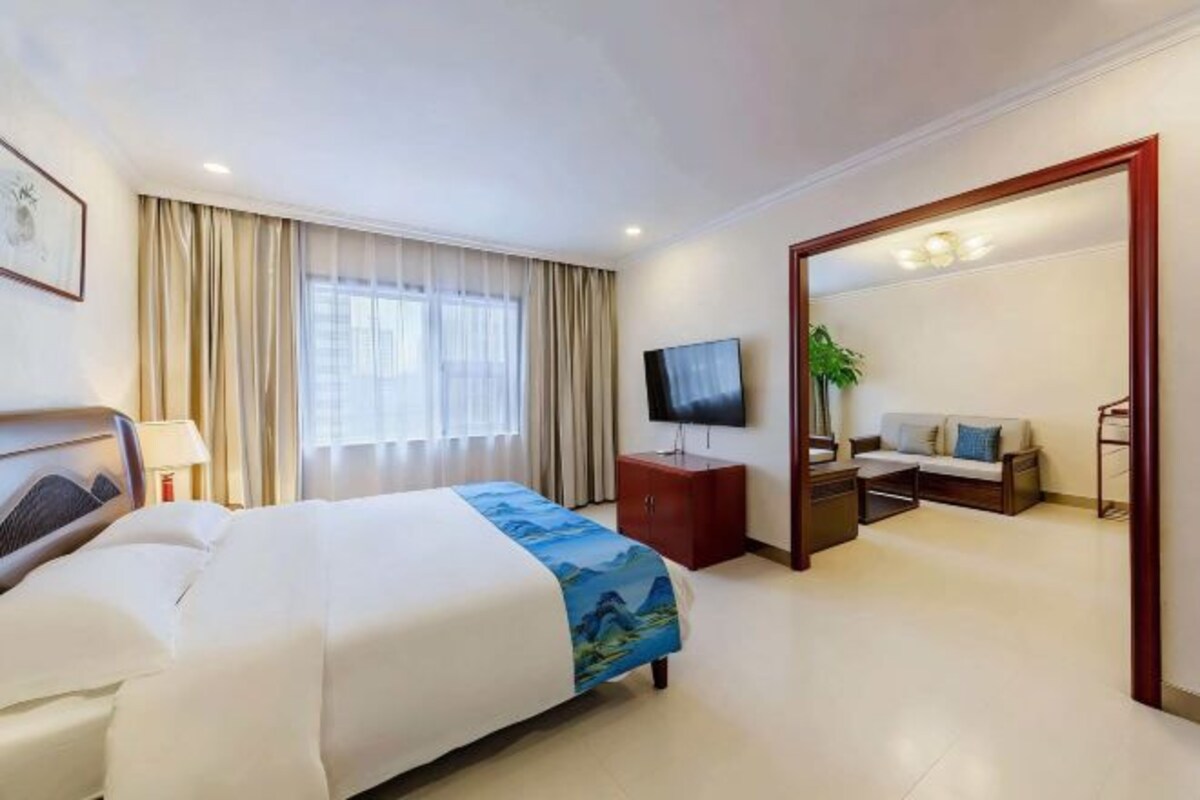Une chambre d’hôtel équipée d’un lit, d’une télévision, d’un bureau, d’un canapé et d’un miroir.