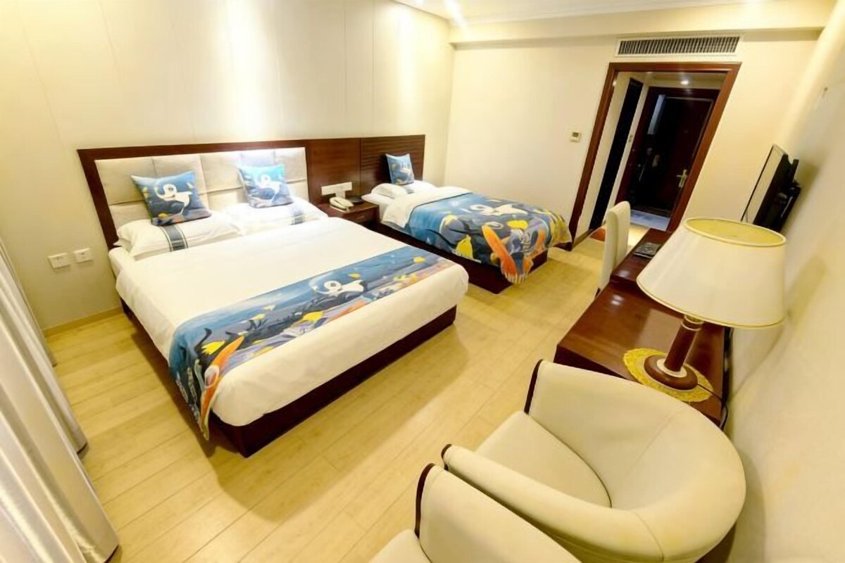 Une chambre d’hôtel avec deux lits, une chaise, une table de chevet et une lampe.
