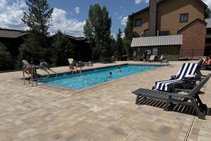 A swimming pool with lounge chairs and a building in the background.