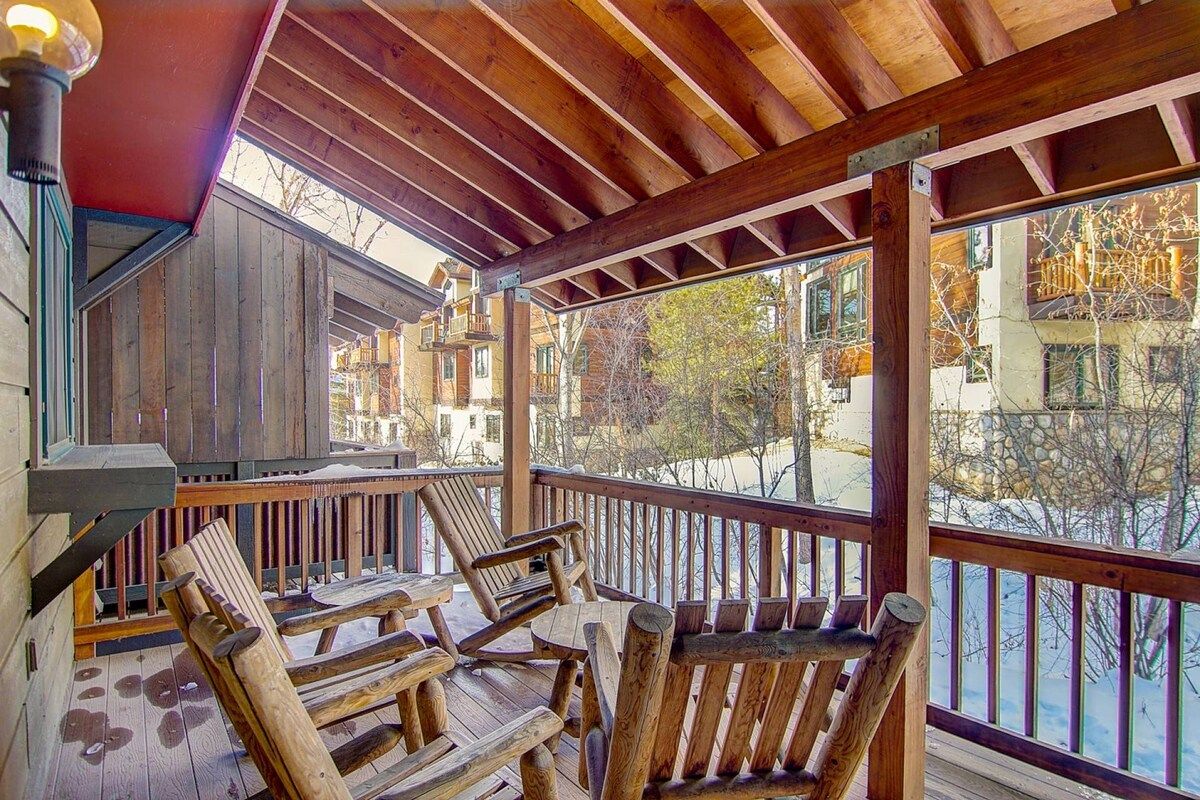 A wooden deck with outdoor seating and a view of buildings in the background.