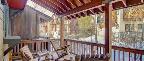 A wooden deck with outdoor seating and a view of buildings in the background.