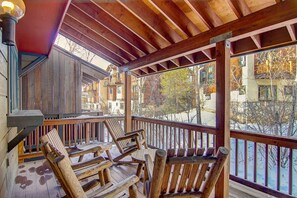 A wooden deck with outdoor seating and a view of buildings in the background.