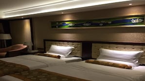 A hotel room with two beds, a headboard with a floral design, a lamp, and a painting on the wall. - Taishan Bojue Hotel (Jiangmen)