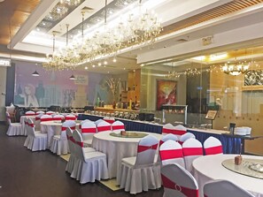 A banquet hall with round tables and chairs, chandeliers, and a large mural on the wall. - Taishan Bojue Hotel (Jiangmen)