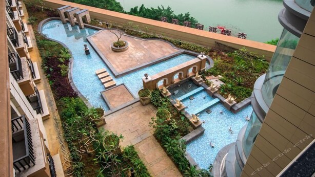 A rooftop pool with multiple sections, surrounded by greenery and a view of a body of water. - Taishan Bojue Hotel (Jiangmen)