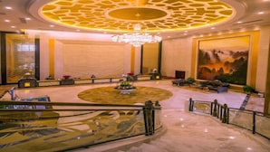 A grand lobby with a circular central area, a chandelier, and a large mural on the wall. - Taishan Bojue Hotel (Jiangmen)