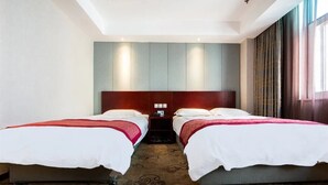 Ein Hotelzimmer mit zwei Betten, einem großen Spiegel und Blick auf die Stadt.