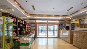 Eine geräumige Lobby mit einer Glasvitrine, einem Empfangstresen und einer grünen Getränkeautomaten.