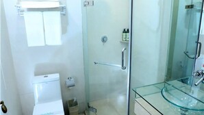 Ein modernes Badezimmer mit Duschkabine aus Glas, einem Waschbecken aus Glas und einer Toilette.