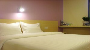 Una cama bien hecha con ropa blanca en una habitación con cabecera de madera.