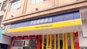 Un hotel con fachada azul y amarilla, dirección web visible y un letrero rojo con caracteres chinos.