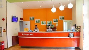 Un mostrador de recepción con una paleta de colores naranja brillante, una pantalla digital y cuadros en la pared.