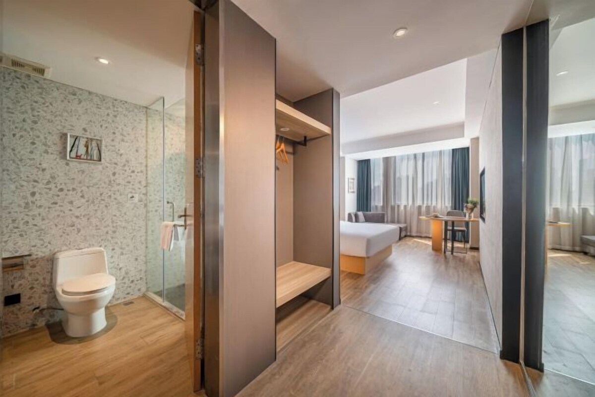 Una habitación de hotel moderna con ducha, inodoro y zona de estar con sofá y mesa.