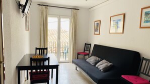 Un espace de vie compact comprenant un canapé, une table à manger et des chaises. Il y a un balcon avec vue.
