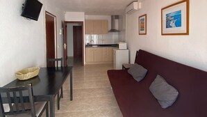 Un espace de vie compact comprenant un coin repas, une kitchenette et un canapé.