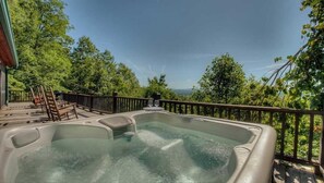 A hot tub on a wooden deck with a view of trees and mountains. - Grand View - Mountain View | Hot tub | Shuffleboard | Air Hockey | Screened in porch (Blue Ridge)