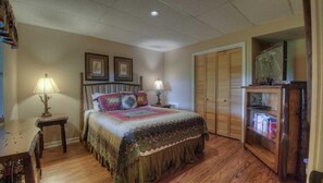 A bedroom with a bed, two bedside lamps, a wooden nightstand, a wooden dresser, and a closet with sliding doors. - Grand View - Mountain View | Hot tub | Shuffleboard | Air Hockey | Screened in porch (Blue Ridge)