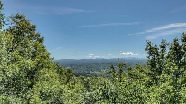 A forested landscape with a clear view of distant mountains. - Grand View - Mountain View | Hot tub | Shuffleboard | Air Hockey | Screened in porch (Blue Ridge)