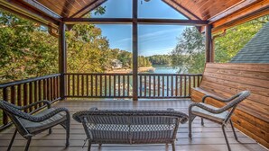 A covered outdoor deck with two wicker chairs and a view of a lake and forest. - Heaven on the Lake - Lakefront | Hot Tub | Fire Pit | Game Room (Blue Ridge)